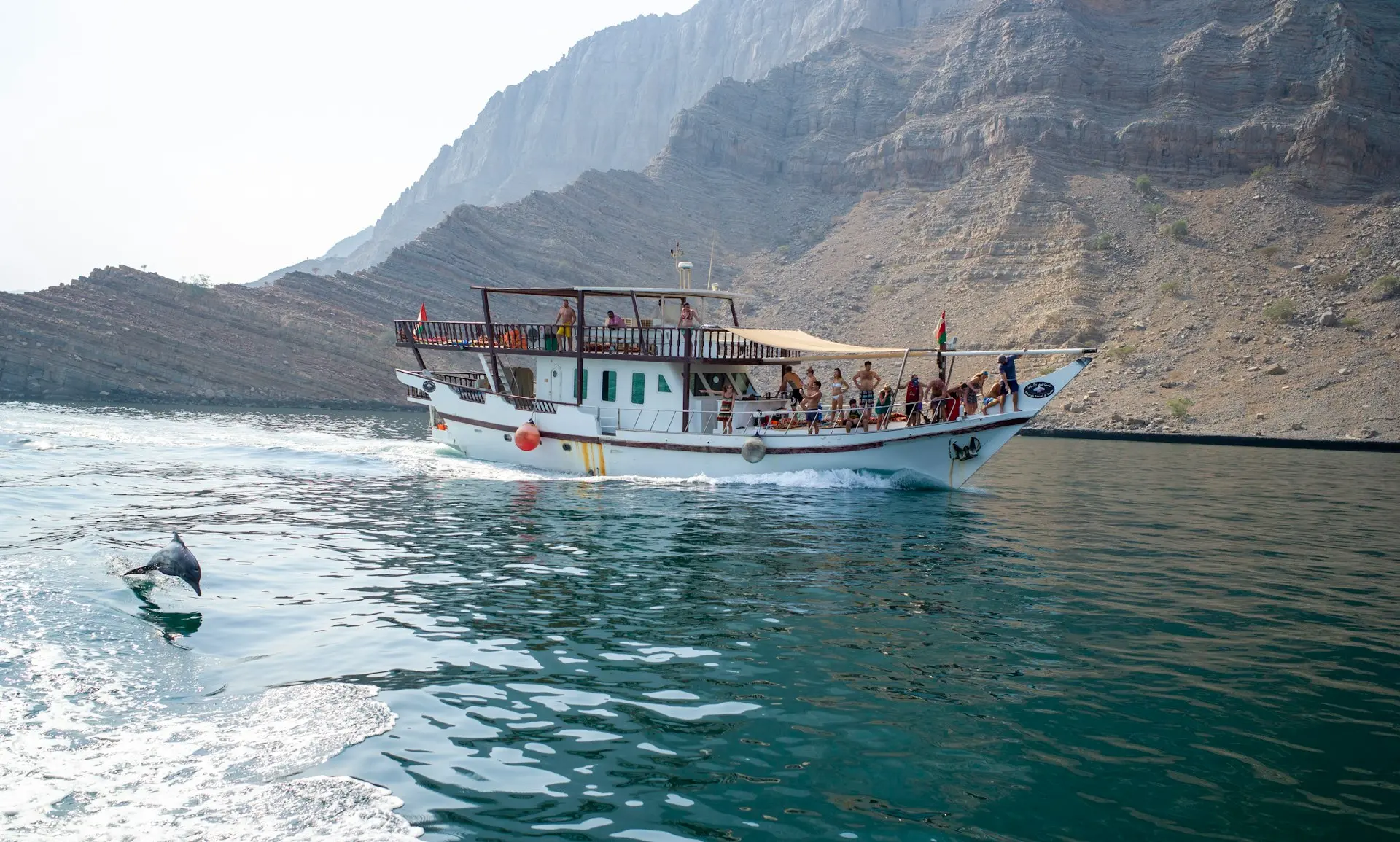 white boat on body of water near mountain during daytime